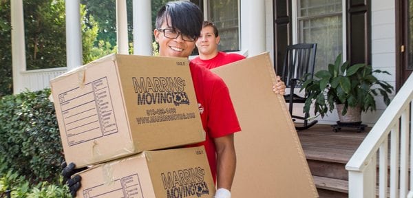 Marrins' employee walking out of a house holding two moving boxes